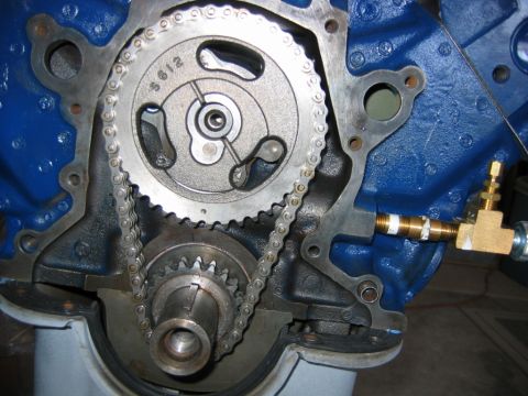 1992 Ford Bronco - Close-up of an engine timing chain assembly with the front cover removed, showing the camshaft sprocket marked '5612' driving a chain down…
