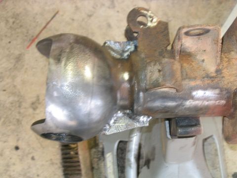 1986 Ford F-150 - A close-up view of a metal component that has been welded and is supported by jack stands. The Supermotors.net logo is visible in the lower…