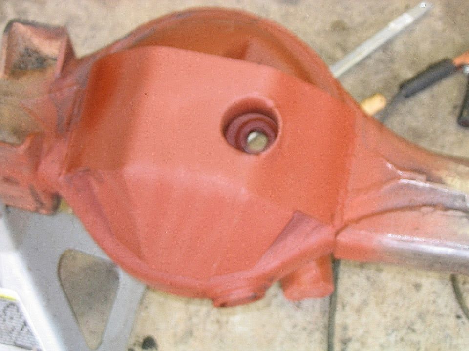 Differential housing painted orange, resting on a jack stand