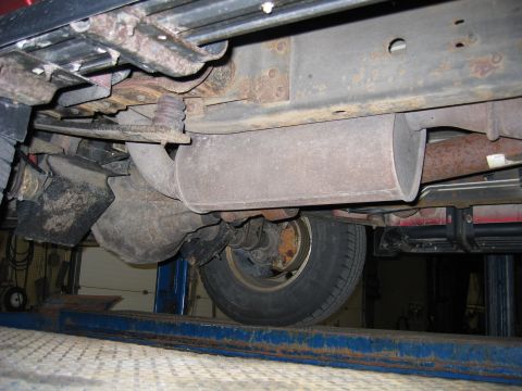 2000 Ford Excursion - The undercarriage of a vehicle, including the exhaust system and a rear tire, is visible while it is raised on a lift.