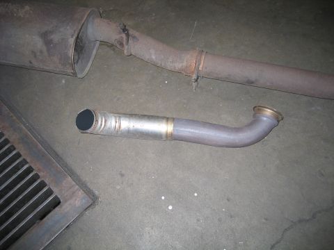 2000 Ford Excursion - A section of exhaust pipe is shown, a flange and a cut end, lying on a concrete surface.