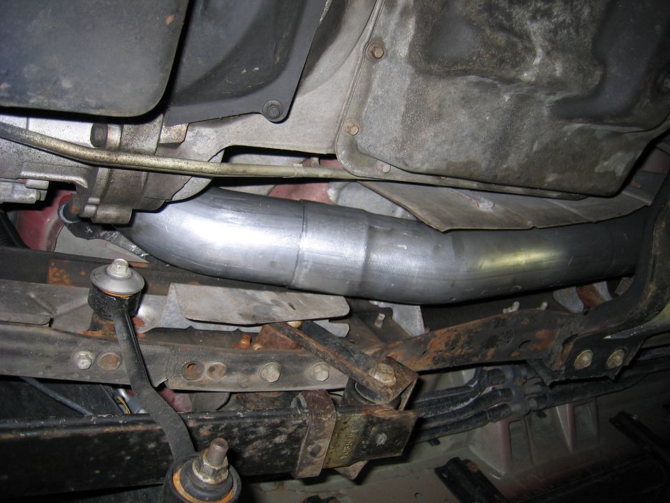 Underside view of a custom exhaust pipe installation with suspension parts visible