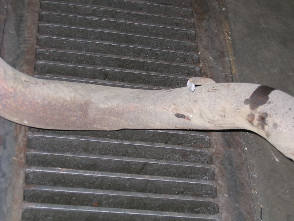 Exhaust pipe section resting on a metal grate