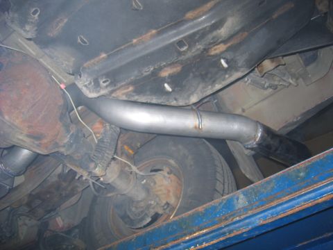 2000 Ford Excursion - Close-up view of the exhaust system and rear axle components of a vehicle, likely undergoing maintenance or repair.