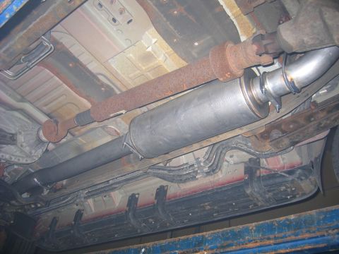 2000 Ford Excursion - The underside of a vehicle reveals a rusty driveshaft and a recently installed exhaust system.