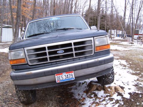 1993 Ford Bronco - Front view of a 1993 Ford Bronco parked on a tree stump during winter.