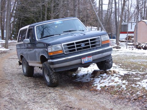 1993 Ford Bronco - 1993 Ford Bronco is positioned on a tree stump in a wooded area.