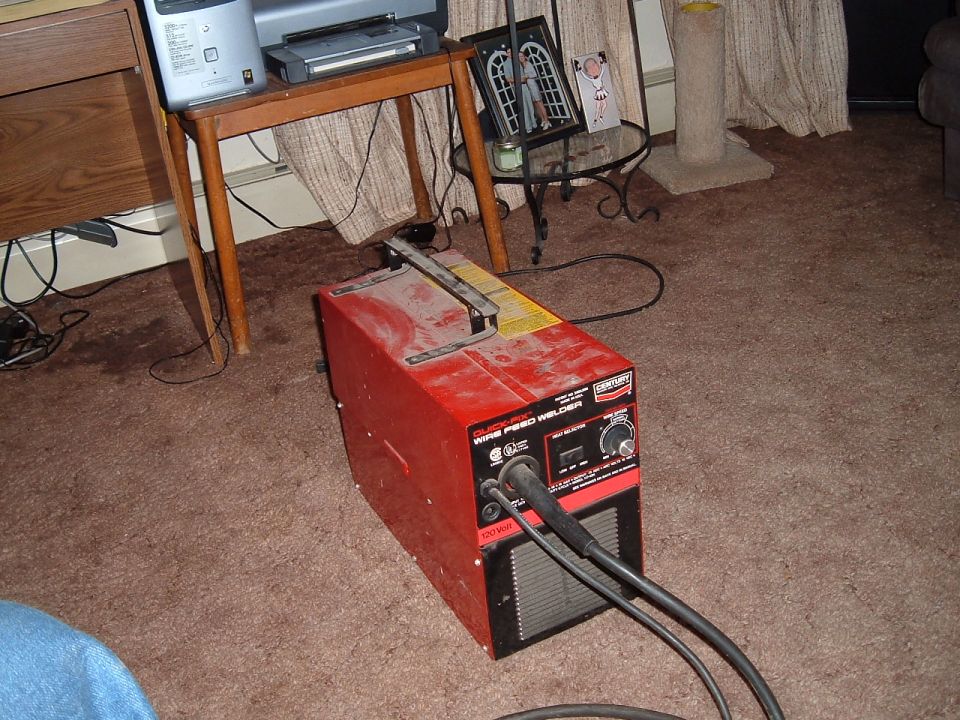 Red wire feed welder with control knobs and cables