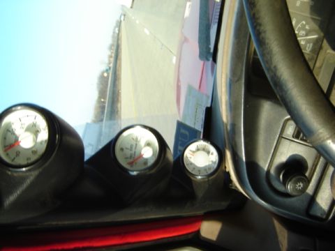 1992 Ford Bronco - Three gauges are mounted on the dashboard of a vehicle, with a view of the road through the windshield.