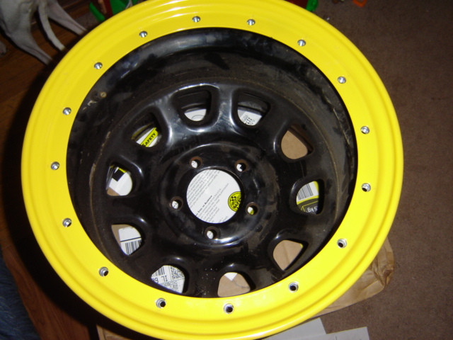 Yellow-painted steel wheel with black center and multiple lug nut holes