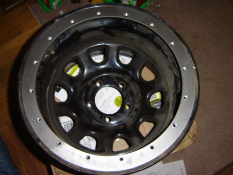 1992 Ford Bronco - Aftermarket wheel with a bolted-on metal trim ring is shown up close.