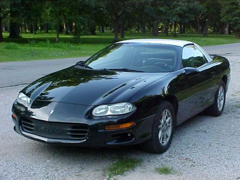 2001 Chevrolet Camaro - A black 2001 Chevrolet Camaro with a white roof is parked outdoors on a gravel surface.
