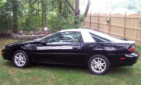 2001 Chevrolet Camaro - Side view of a black 2001 Chevrolet Camaro a white t-top roof.