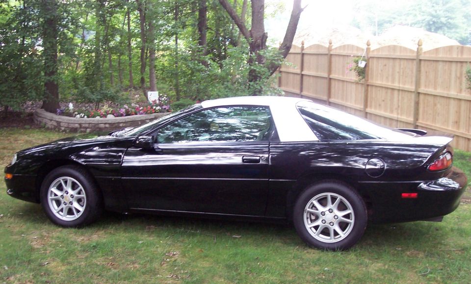 Black fourth-generation Chevrolet Camaro coupe with white roof parked on grass