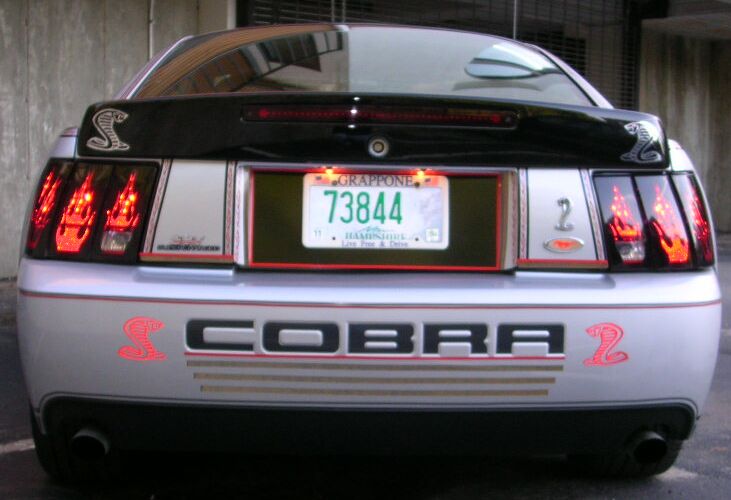 Rear of silver Mustang with "COBRA" badging and snake emblems