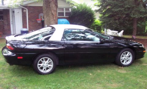 2001 Chevrolet Camaro - A black 2001 Chevrolet Camaro with a white t-top is parked on a grassy lawn in front of a brick house.