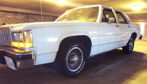 1985 Ford Crown Victoria LTD - This white 1985 Ford Crown Victoria LTD is shown from the front three-quarter view.