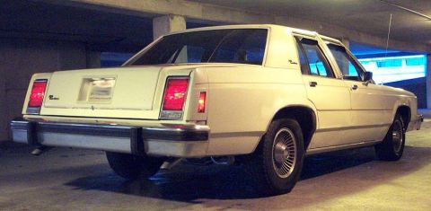 1985 Ford Crown Victoria LTD - This sedan's rear end features distinct rectangular taillights and a prominent chrome bumper, indicative of its era.