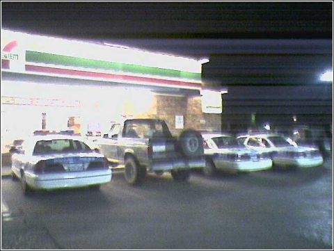 1993 Ford Bronco - Police cars and a pickup truck are parked in front of a 7-Eleven store.