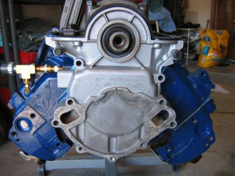1992 Ford Bronco - Front view of a freshly rebuilt Ford V8 engine block painted blue with a bare aluminum timing cover, front crankshaft seal, and a cast mark…