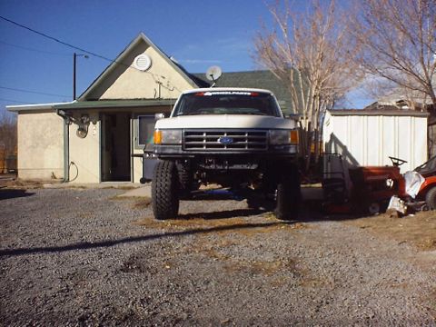 1988 Ford Bronco - This lifted Ford truck, likely from the late 1980s, is parked in front of a residential building.