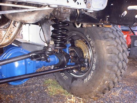 1988 Ford Bronco - Front axle and suspension components of a 4x4 vehicle, a large off-road tire.