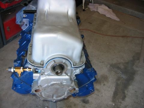 1992 Ford Bronco - Rear view of an engine block painted Ford blue, sitting on an engine stand with a bare aluminum oil pan installed and the rear main seal ho…