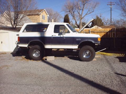 1988 Ford Bronco - This two-tone blue and white Ford Bronco is shown from the side with its hood raised, revealing the engine, propped open.