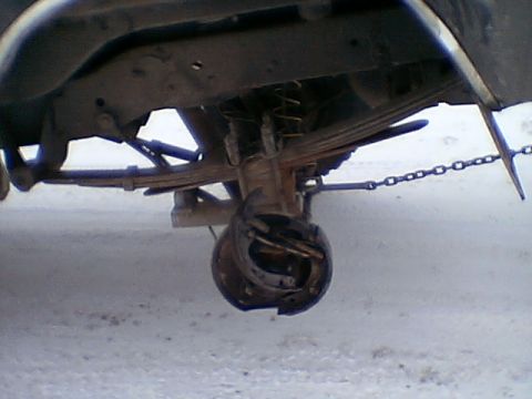 1979 Ford Bronco - Close-up view of the rear suspension and axle components of a vehicle, showing signs of wear and damage.
