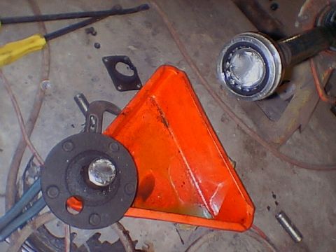 1979 Ford Bronco - Various automotive parts, including a bearing and a flange, are laid out on a concrete surface next to an orange funnel.