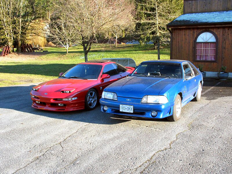 Red 1994 Ford Probe and blue Ford Mustang parked on asphalt