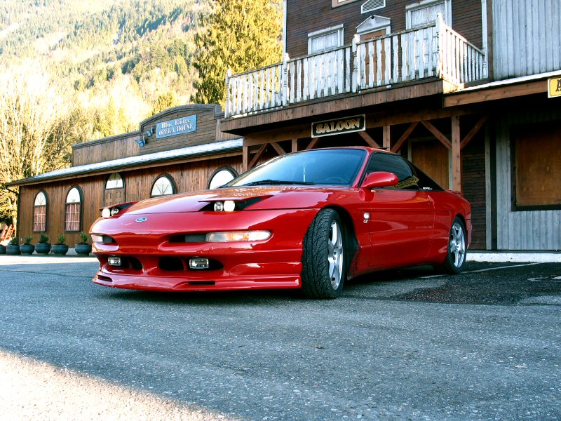 Red 1994 Ford Probe parked in front of a saloon
