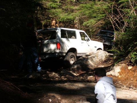 1980 Ford Bronco - A white 1980 Ford Bronco navigates a challenging rocky path, with another vehicle visible behind it.