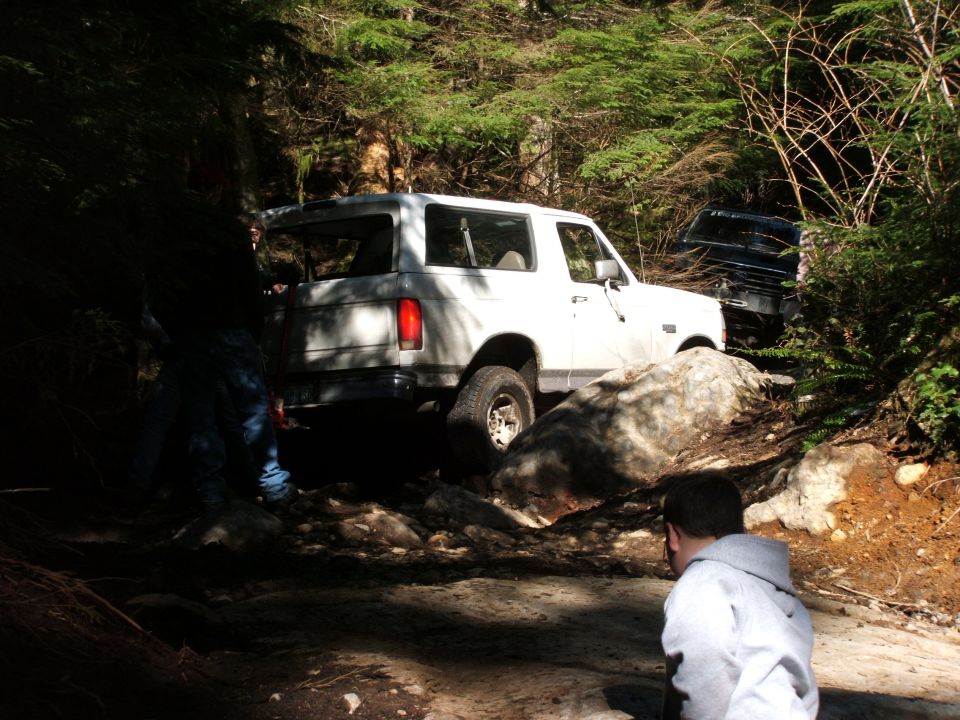 White 1980 Ford Bronco on a rocky trail, rear 3/4 view