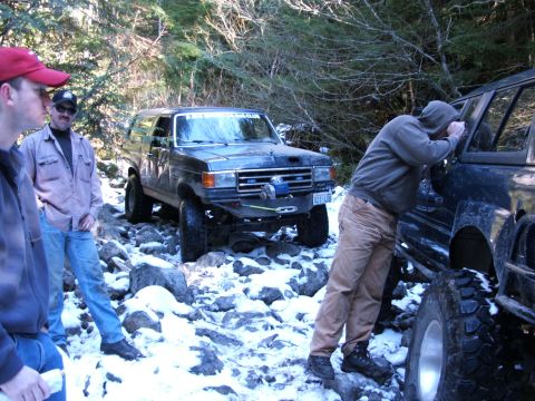 1980 Ford Bronco - A modified 1980 Ford Bronco navigates a snowy, rocky trail with several people around.