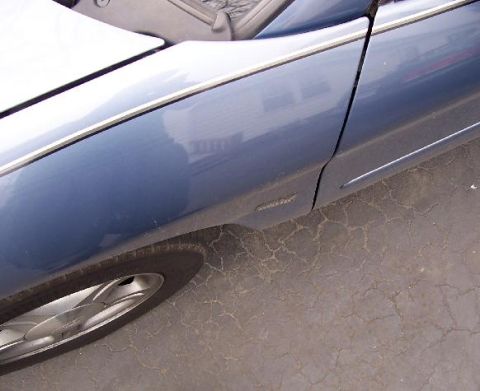 1999 Ford Taurus - The side profile of a blue 1999 Ford Taurus shows its distinct body lines and alloy wheel.