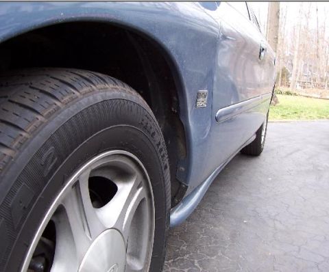 1999 Ford Taurus - Close-up of a 1999 Ford Taurus's side panel, wheel, and door badge.