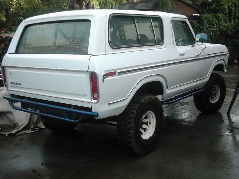 1978 Ford Bronco - Rear view of a white 1978 Ford Bronco, modified with a blue rear bumper and off-road tires.