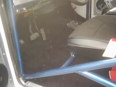 1978 Ford Bronco - The interior of a vehicle is shown, a roll cage and manual transmission components.