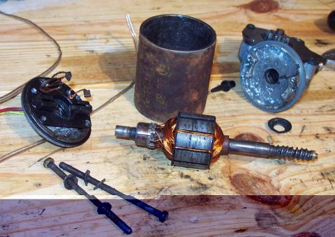 1985 Ford Crown Victoria LTD - Disassembled window motor parts laid out on a wooden workbench.