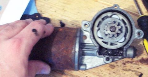 1985 Ford Crown Victoria LTD - Close-up of a rusty window motor assembly with gears visible.