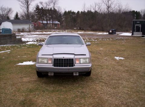 1992 Lincoln Mark VII - A silver sedan is parked in a grassy area with a few patches of snow visible.