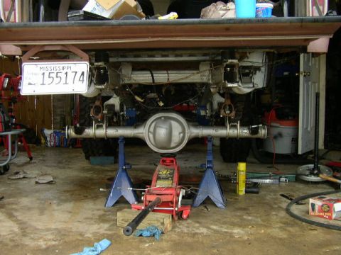 1995 Ford Bronco - The rear axle assembly of a vehicle is supported by jack stands in a garage setting, with a Mississippi license plate in view.