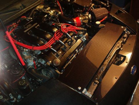 1995 Ford Probe - The engine bay of a 1995 Ford Probe shows a V6 engine with red spark plug wires and carbon fiber trim.