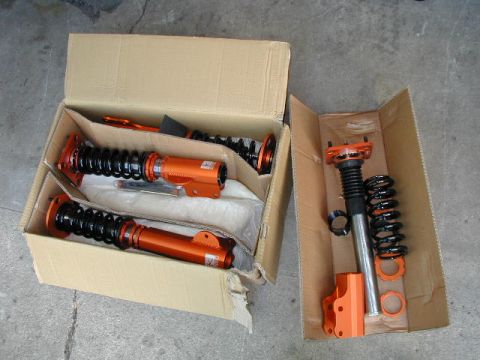 1994 Ford Probe - Unboxed coilover suspension components are laid out on a concrete surface, ready for installation.