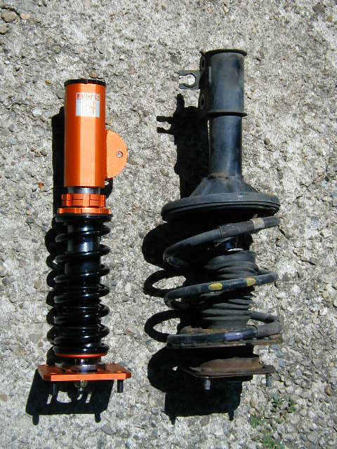 1994 Ford Probe - Comparison of an aftermarket coilover and a stock strut assembly against a concrete background.