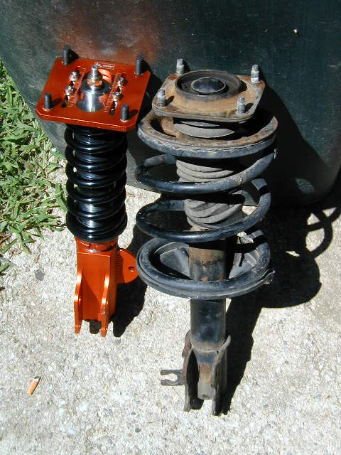 1994 Ford Probe - Comparison of a new orange adjustable coilover suspension part with an older, used strut assembly.