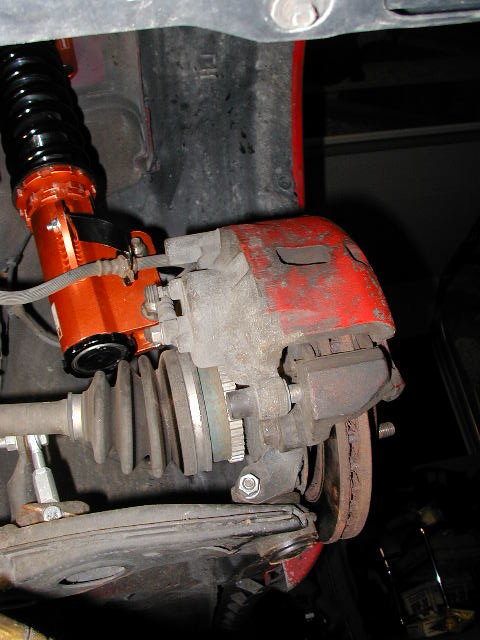 1994 Ford Probe - Close-up view of an orange coilover suspension system and a red brake caliper, likely part of a vehicle's front suspension.