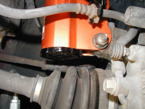 1994 Ford Probe - Detail of an orange automotive part, likely a reservoir, with associated brake lines and suspension components.