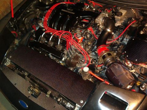 1995 Ford Probe - Close-up view of a modified engine bay, red spark plug wires and an aftermarket air intake system.